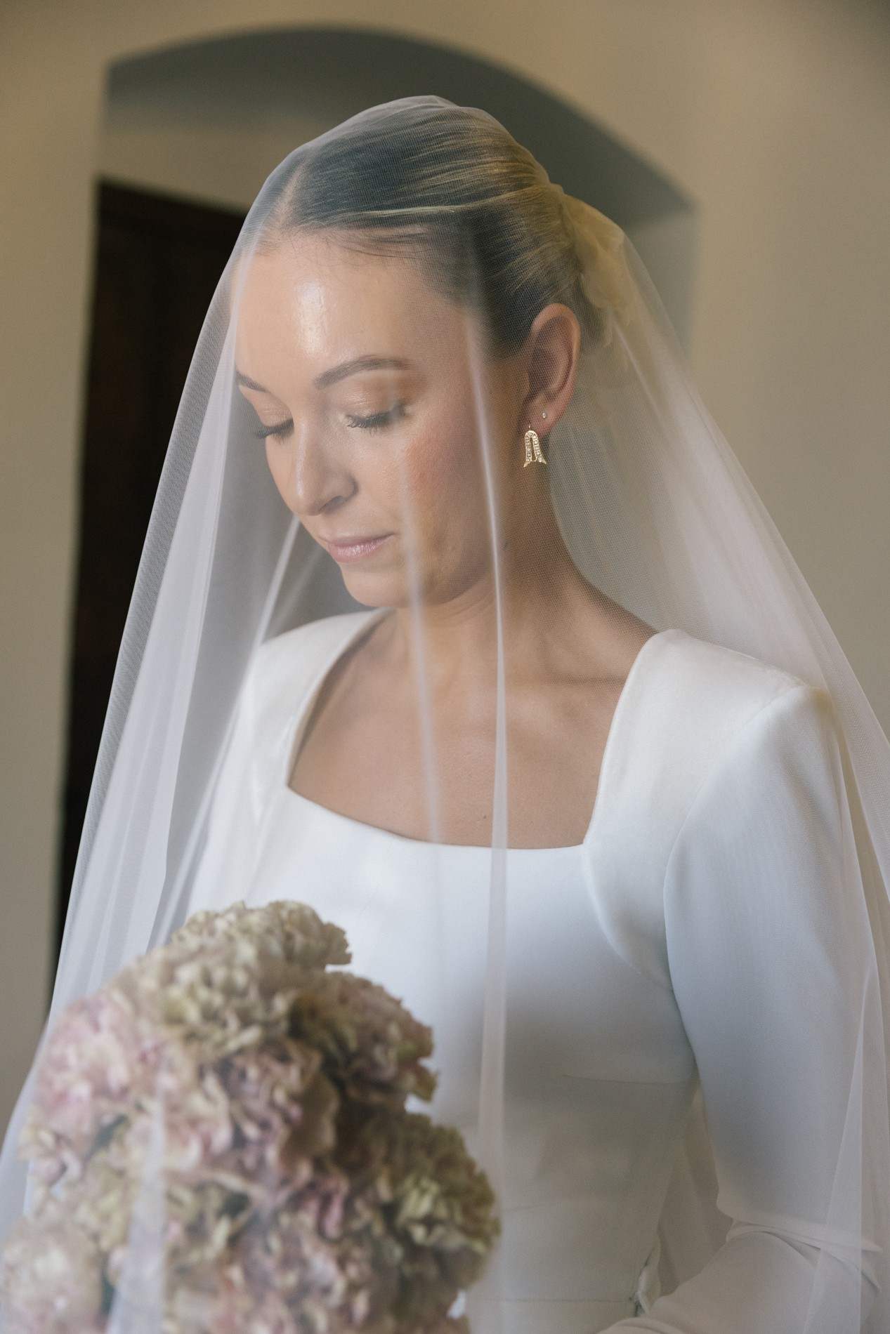 Retrato de la novia bajo el velo con un ramo de hortensias